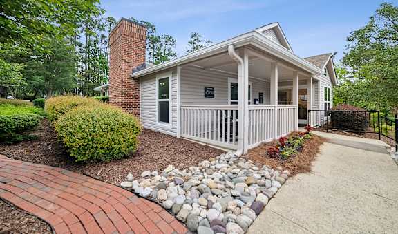 the front of a white house with a walkway and rocks