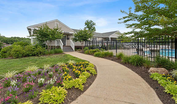 a sidewalk in front of a house with a pool