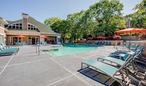 A large outdoor swimming pool area with sun loungers and a building in the background. at Beacon Ridge Apartments, Greenville, SC, 29615