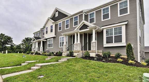 a row of houses with a grass yard and a cloudy sky