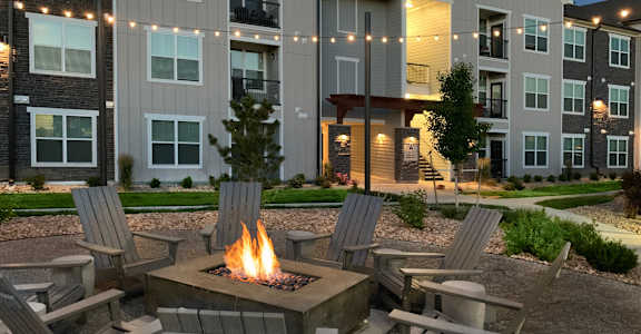 a fire pit and chairs in a courtyard with an apartment building at Watermark at Harvest Junction, Colorado