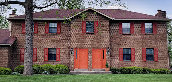 a brick house with red doors and a tree  at The Villas at Kingswood, West Chester, 45069