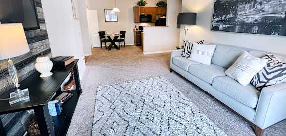 A living room with a grey couch, a patterned rug, and a black and white photo on the wall.