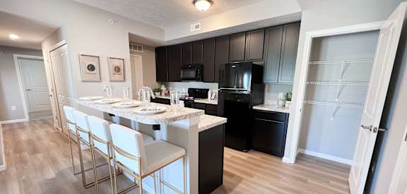 A kitchen with black cabinets and a white island.