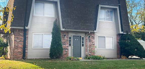 a brick house with a green door and a lawn