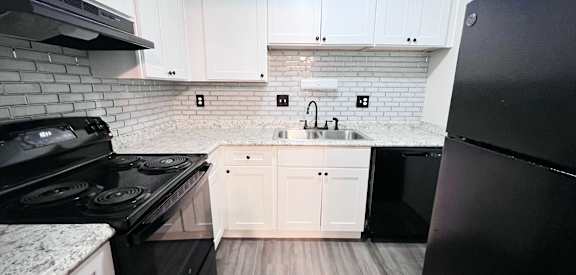 A kitchen with black appliances and white cabinets.