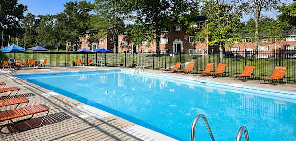 a swimming pool with orange chairs and a fence around it