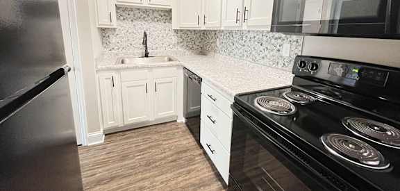a kitchen with black appliances and white cabinets at 450 on Keeneland Apartments, Minnesota