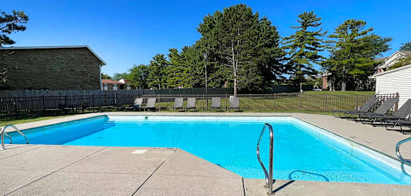 a swimming pool with chairs and a fence around it  at Eagle Crest Apartments, Ohio