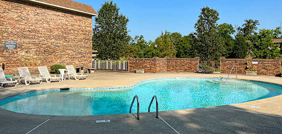 a resort style pool with chairs around it and a brick building  at Grace Court, Ft. Mitchell, 41017