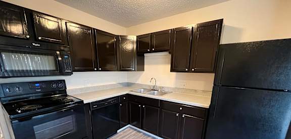 an empty kitchen with black appliances and wood flooring at Quail Meadow Apartments, Ohio, 45240