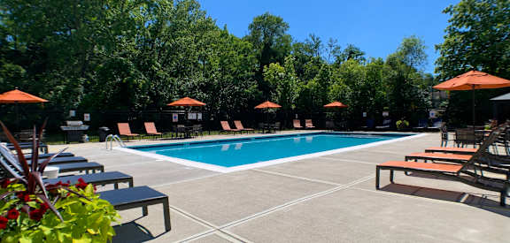 a swimming pool with chairs and umbrellas around it at Fox Run Apartments, Cincinnati