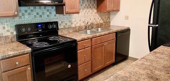 a kitchen with black appliances and wooden cabinets  at Forest Creek Apartments, Middletown