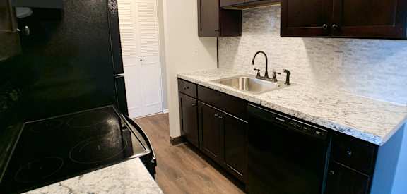 a kitchen with black appliances and white marble counter tops at Crown Pointe Apartments, Covington
