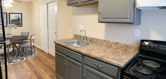 a kitchen with gray cabinets and a sink and a stove  at Crown Court Apartments, Florence, KY