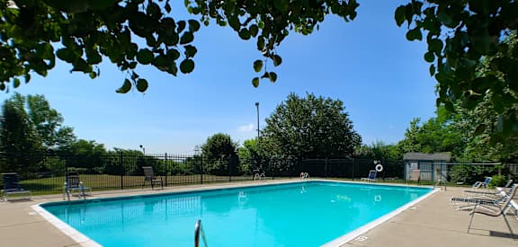 a swimming pool with chairs and a fence around it  at Knobs Pointe Apartments, New Albany, Indiana