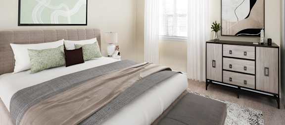 A bedroom with a large bed and a dresser with a mirror. at West Pointe Apartments, Apartments, Burlington, NC