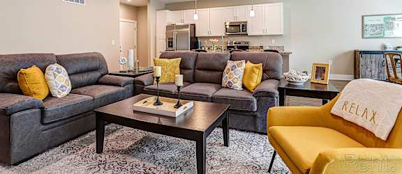 A living room with grey couches and a yellow chair.