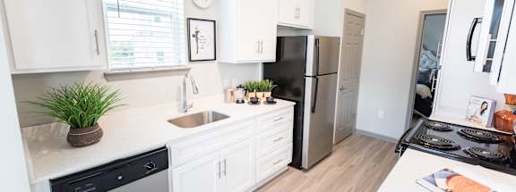A kitchen with white cabinets and a black fridge.