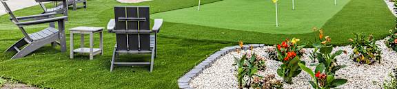 A miniature golf course is surrounded by chairs and flowers.