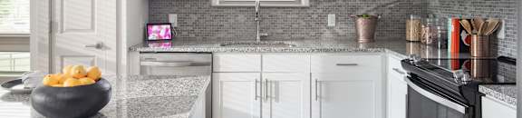 A modern kitchen with white cabinets and a granite countertop.