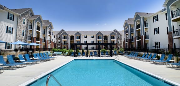 our apartments offer a swimming pool with blue chairs and an apartment building in the background at Parkway Trails, Florence, KY, 41042