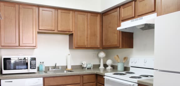a kitchen with white appliances and wooden cabinets at Walnut Creek Townhomes, Cincinnati, OH