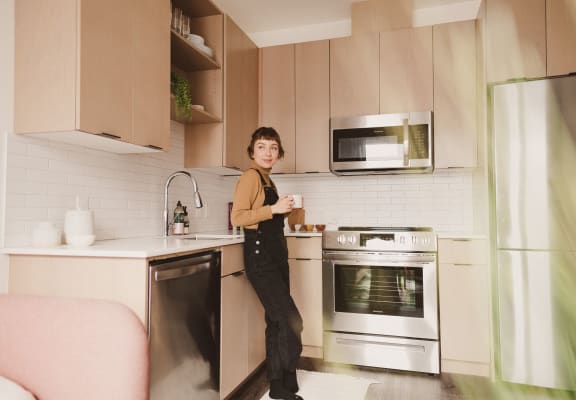 Woman Holding Coffee Cup Standing in Kitchen