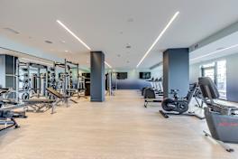 A gym with a variety of equipment including weights, treadmills, and stationary bikes.