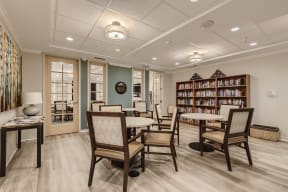a community room with tables and chairs and a library