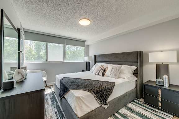 A bedroom with a large bed and a window overlooking trees.