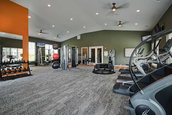 a gym with weights and cardio equipment in a home with green walls at Watermark at Harvest Junction, Colorado