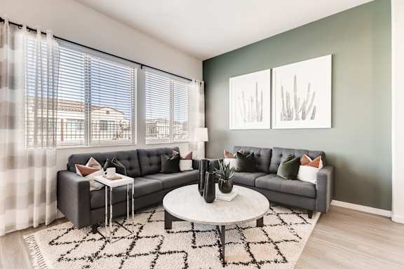 A living room with a grey couch, a white coffee table, and a rug. at Avilla Meadows  Apartments, Surprise, AZ, 85379