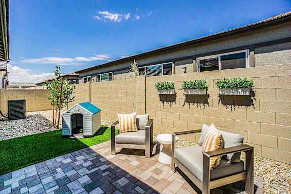 A patio with a couch, chair, and a dog house.
