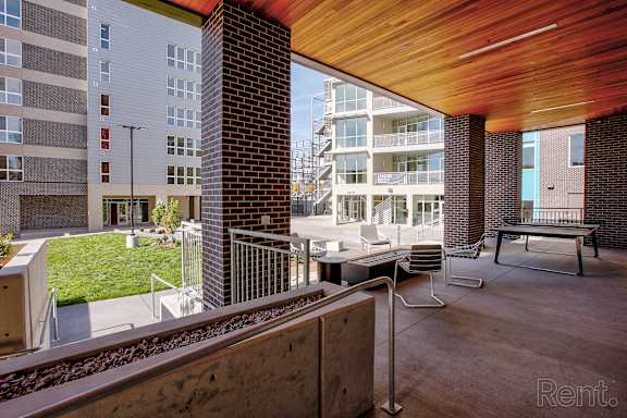A modern outdoor seating area with a wooden ceiling and a view of a train track.