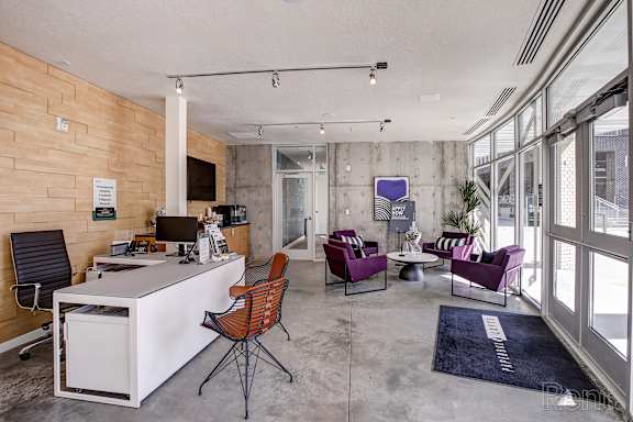A modern office space with a white desk, purple chairs, and a wooden wall.