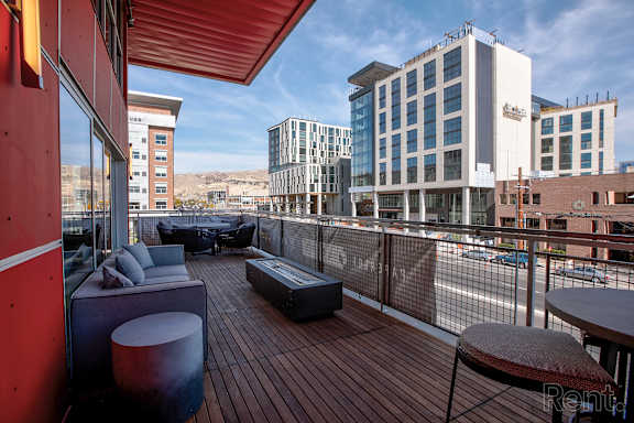 A balcony with a red railing and a table and chairs.