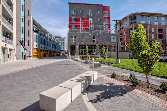 A modern courtyard with a bench and a tree in front of apartment buildings.