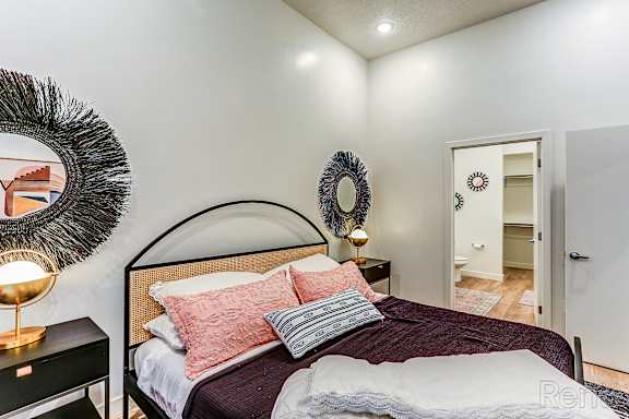 A bedroom with a large bed and a mirror on the wall.