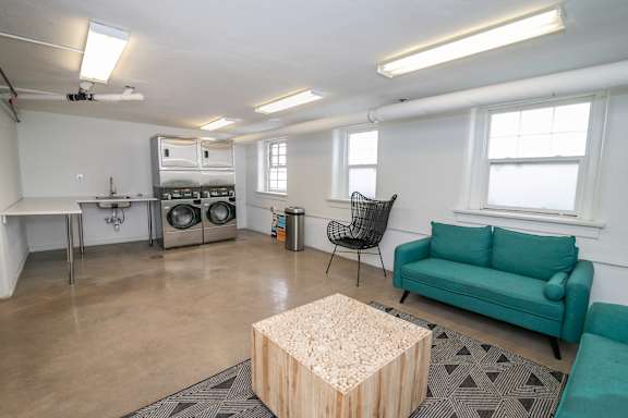 A room with a green couch, a wooden table, and a black chair.