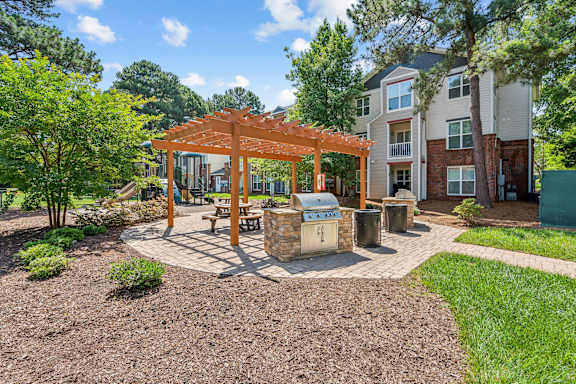 a patio with a picnic table and a grill