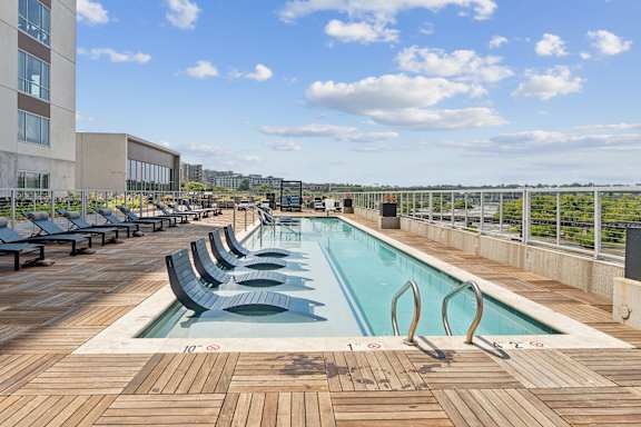 A large outdoor pool with wooden decking and lounge chairs.