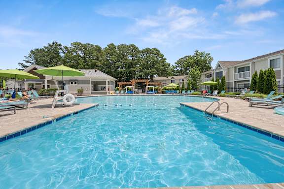 A large swimming pool with a blue tinted water and a sunny day.