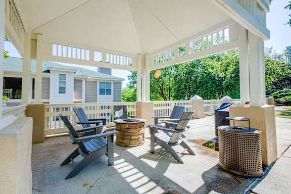 a covered patio with chairs and tables and a house in the background at Beacon Ridge Apartments, Greenville, SC, 29615