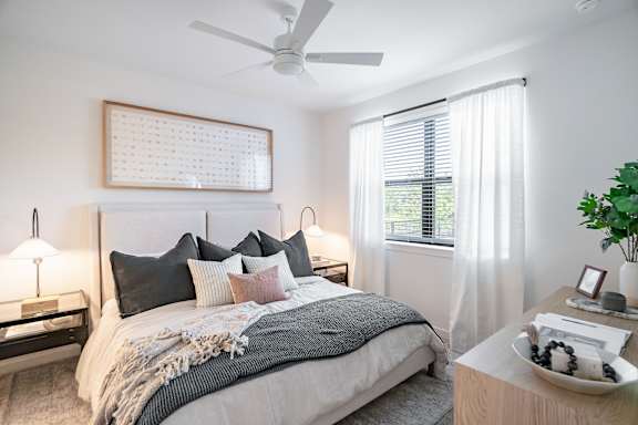 A bedroom with a bed, nightstand, and a plant.