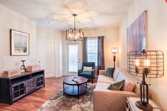 A living room with a brown couch, a coffee table, and a chandelier.