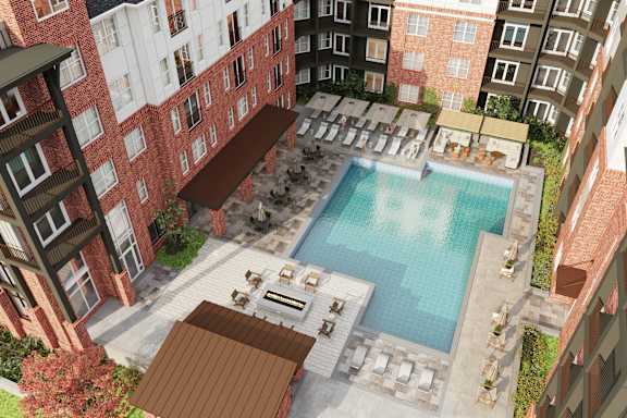 A pool surrounded by a patio with lounge chairs and umbrellas.