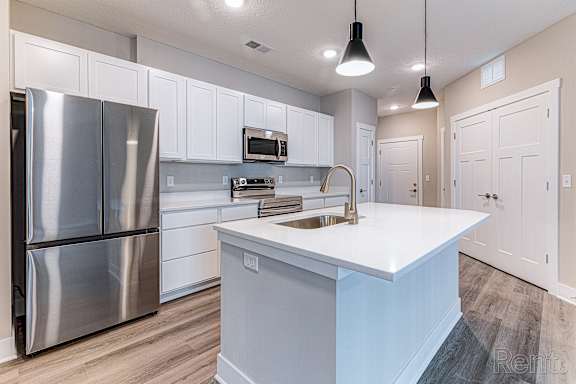 A modern kitchen with a stainless steel refrigerator and white cabinets.