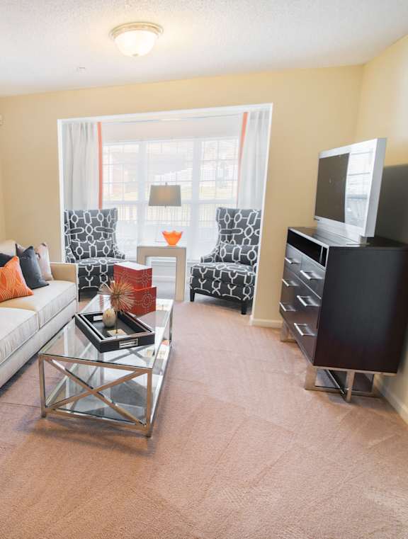 A living room with a white couch and a painting on the wall.