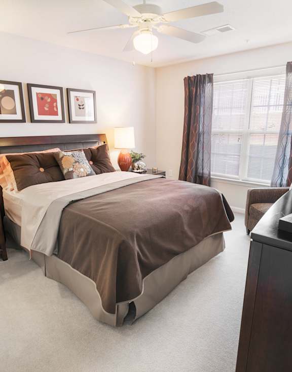 A bedroom with a large bed, a nightstand, and a ceiling fan.
